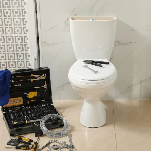A newly installed white ceramic toilet surrounded by a professional tool case, wrenches, and plumbing supply materials on a bathroom floor.