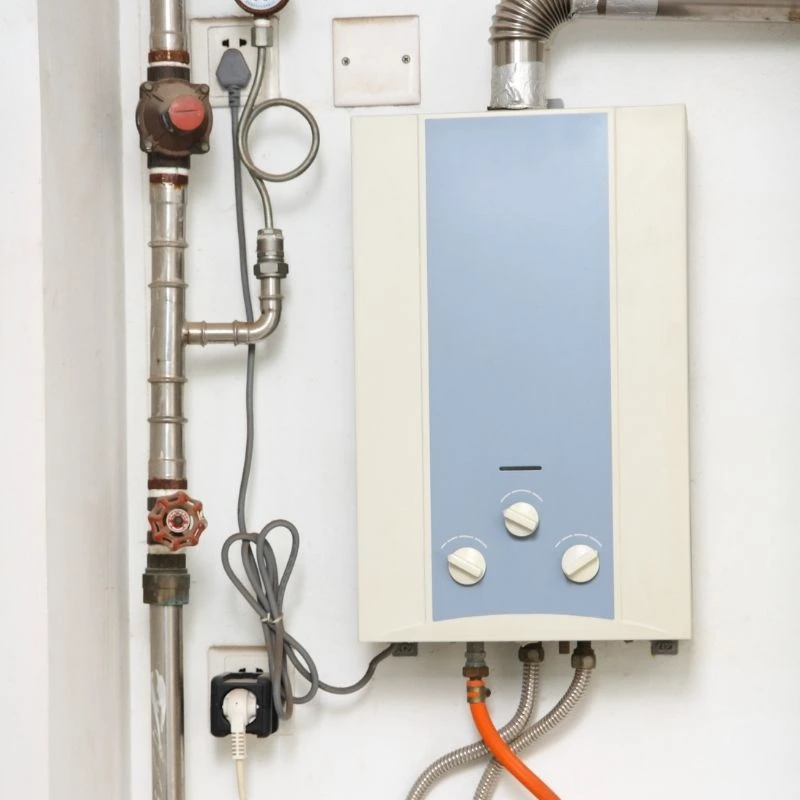 An aging, outdated wall-mounted tankless water heater scheduled for a high-efficiency system replacement and gas line upgrade in a Niles property.