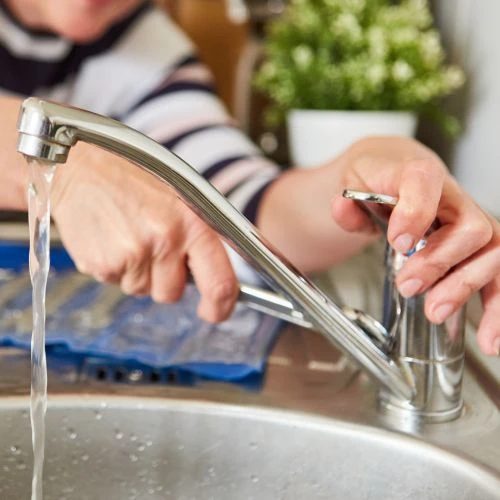 Close-up of a worker testing the steady water flow from a newly installed chrome single-handle kitchen faucet.