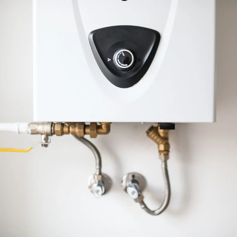 Close-up of secure brass water line connections and a gas valve on a newly installed, energy-efficient tankless water heater in a Niles home.