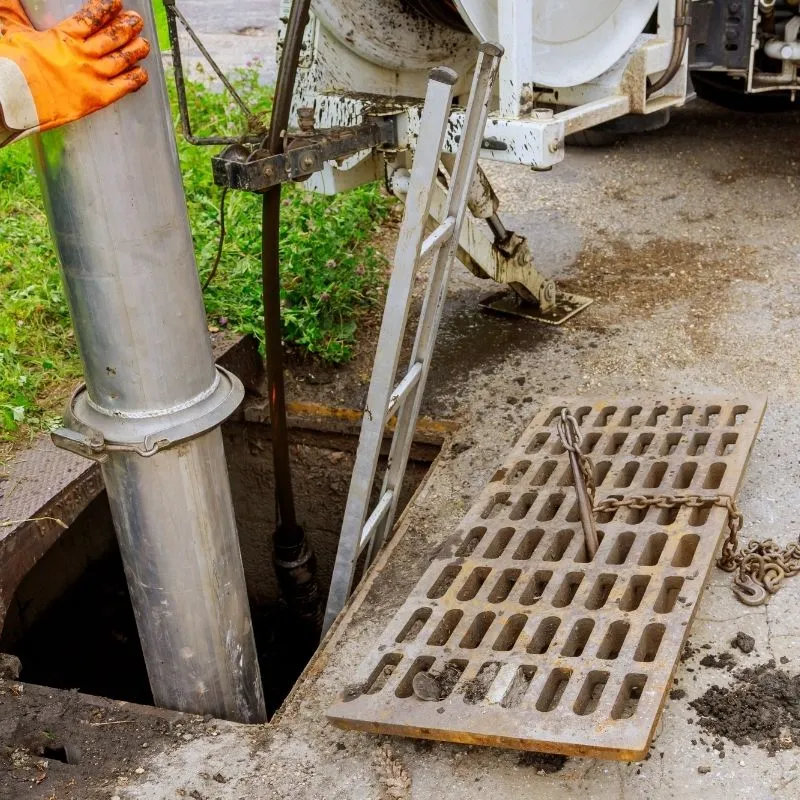 Elevate Plumbing technician guiding a heavy-duty red sewer rodding cable into an outdoor cleanout to safely punch through a severe main line backup in Skokie.