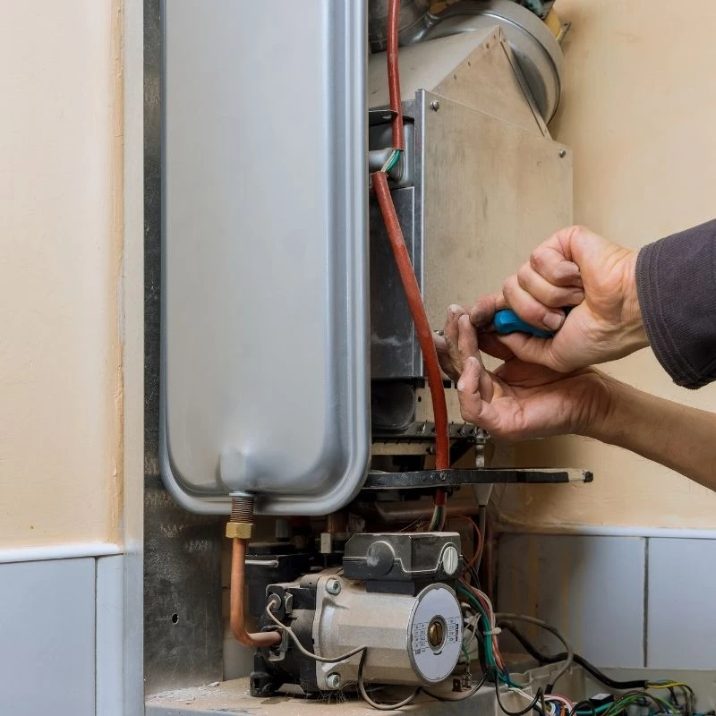 Expert plumbing technician fine-tuning internal electrical components during a professional tankless water heater installation in Niles.