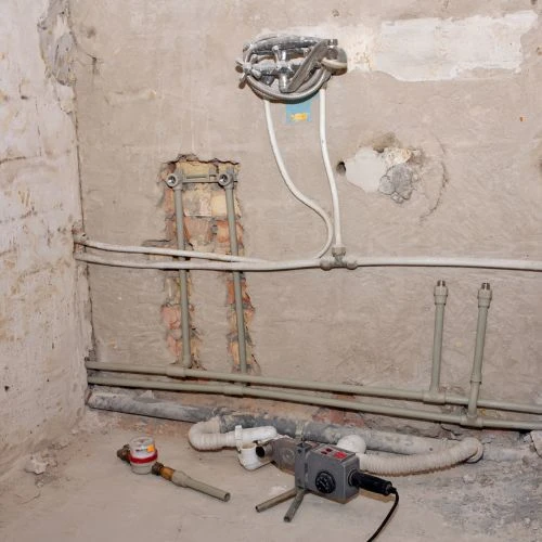 Exposed interior masonry wall showing old plumbing lines being stripped out and upgraded during a whole-home pipe replacement project.
