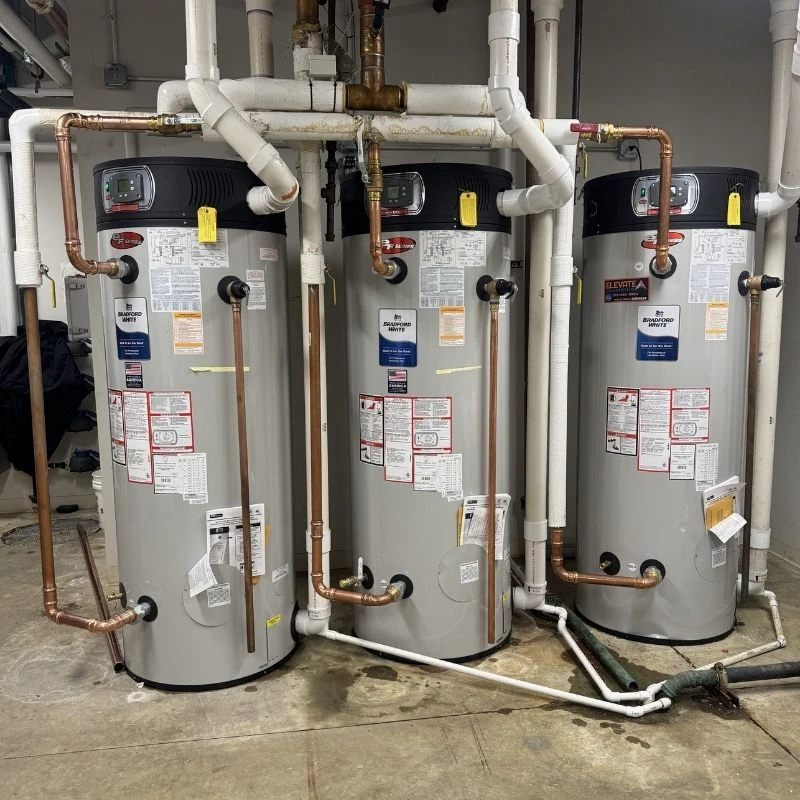 High-capacity commercial tank water heater installation featuring three Bradford White units with complex copper manifold piping for a large facility in Northwest Chicago.