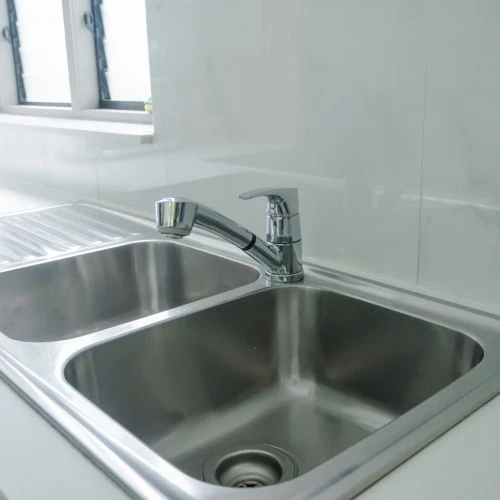 Modern polished chrome pull-out faucet installed on a clean stainless steel double-bowl kitchen sink.