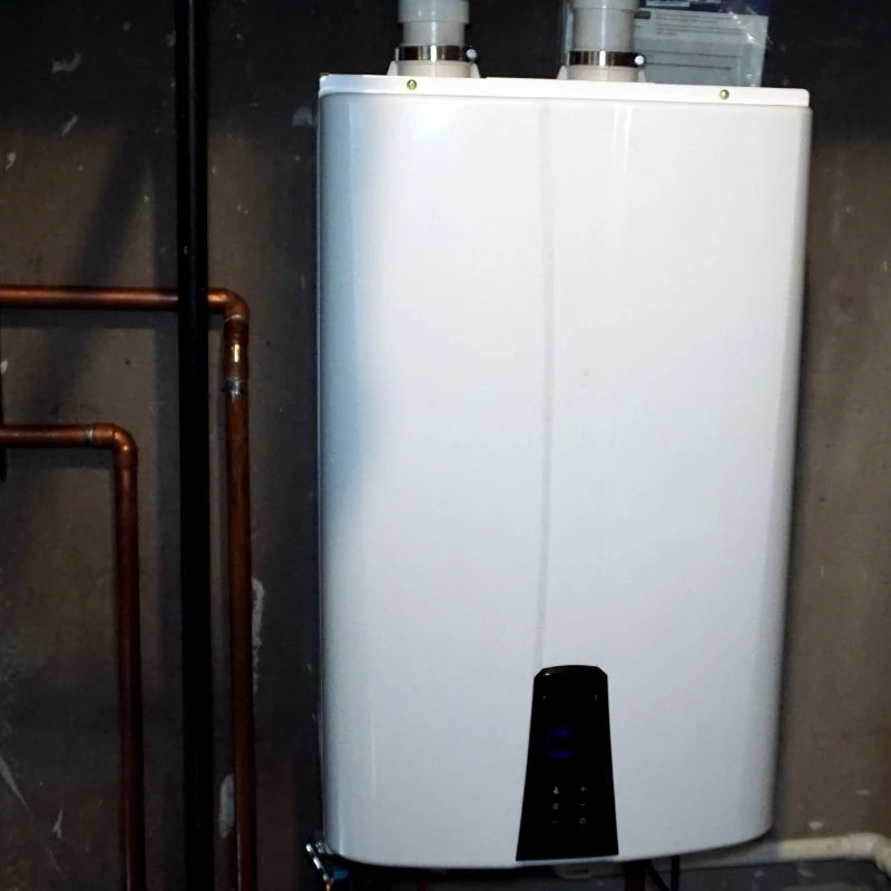 Sleek, modern tankless water heater upgrade featuring a digital control panel and professional copper piping installed in a Niles residential basement.