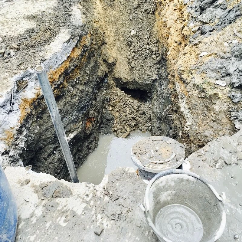 Excavated dirt trench exposing a blocked main sewer line filled with wastewater prior to heavy-duty rodding and pipe repair in Park Ridge.